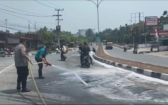 Bhabinkamtibmas bersama Damkar dan Masyarakat Bersihkan Tumpahan Minyak